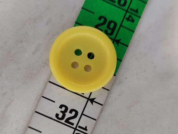 Κουμπί κίτρινο πλαστικό με τέσσερις τρύπες. Μέγεθος 20ΜΜ