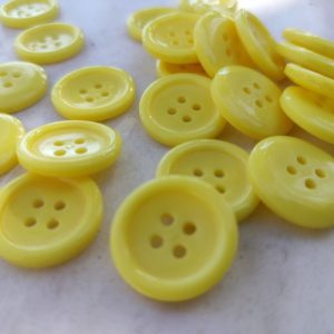 Κουμπί κίτρινο πλαστικό με τέσσερις τρύπες. Μέγεθος 20ΜΜ